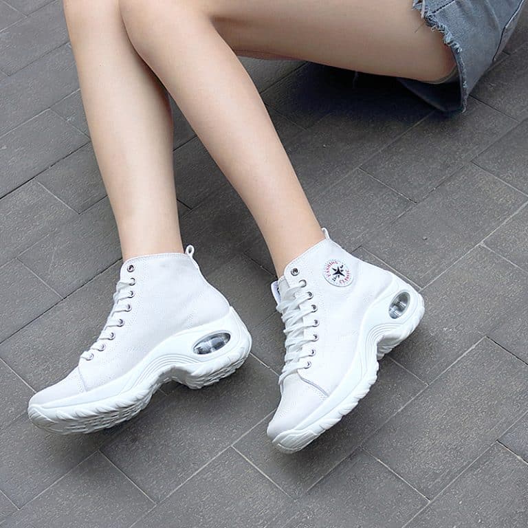 White women's sneakers with wavy sole and decorative stitching.