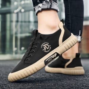 Black men's sneakers with thick beige soles, worn with jeans, ideal for feet.