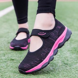 Comfortable hook-and-loop shoes for women in black with pink details, on a grass background.