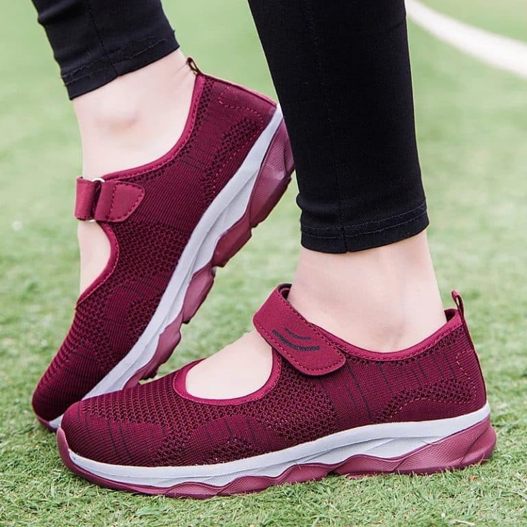 Comfort shoes with velcro for women in dark red, on a cobblestone floor.