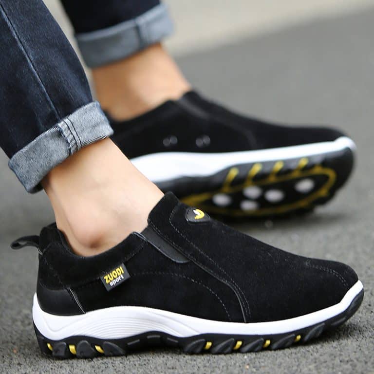 Casual black walking shoes for men, worn with cuffed jeans.