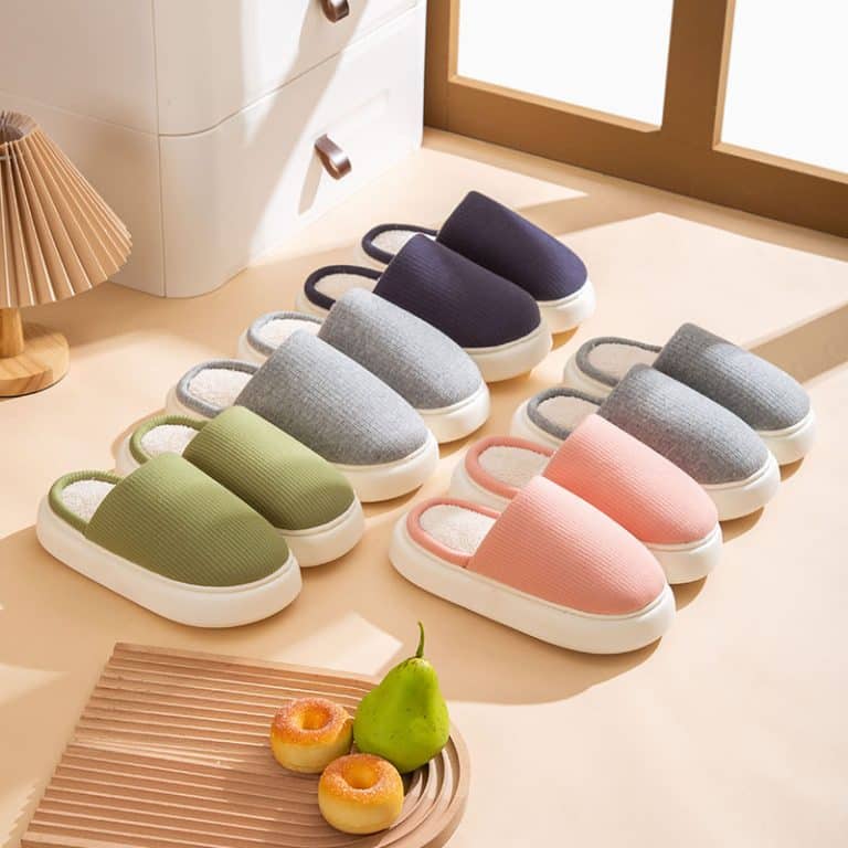 Collection of orthopedic cotton slippers in different colors on a light wooden floor.