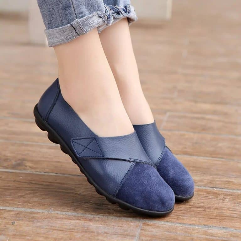 Comfortable women's moccasins with black flexible sole and X-strap on blue background.