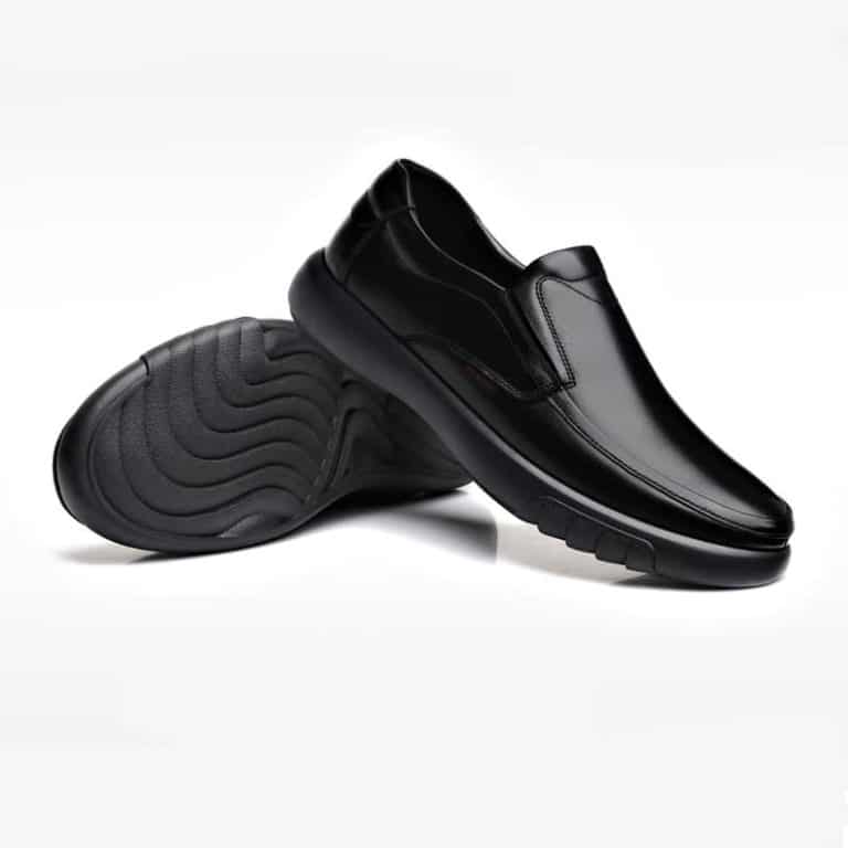 Pair of men's black orthopedic office shoes, side view and sole, on white background.