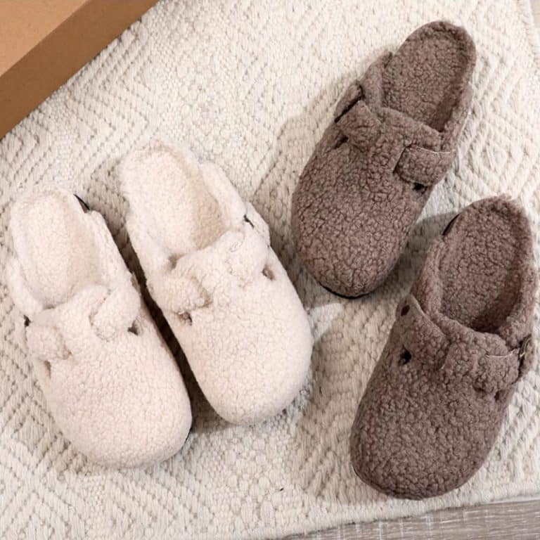 Pair of soft wool slippers, one in beige and one in taupe, side by side on a textured rug.