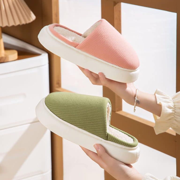 Orthopedic cotton slippers for women, closed, pink and green, held in hands near a window.