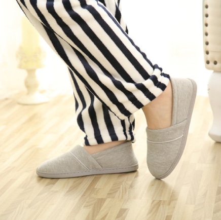 Comfortably settled feet in gray slippers, contrasting with the striped pants.