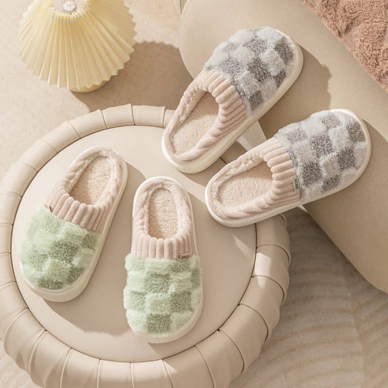 Four pairs of orthopedic slippers on a circular footstool, in green faux fur and gray checkerboard.