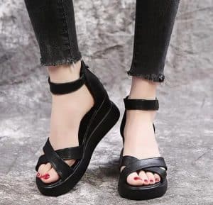 Black strap sandals with comfort sole, buckle strap, and red nail polish.