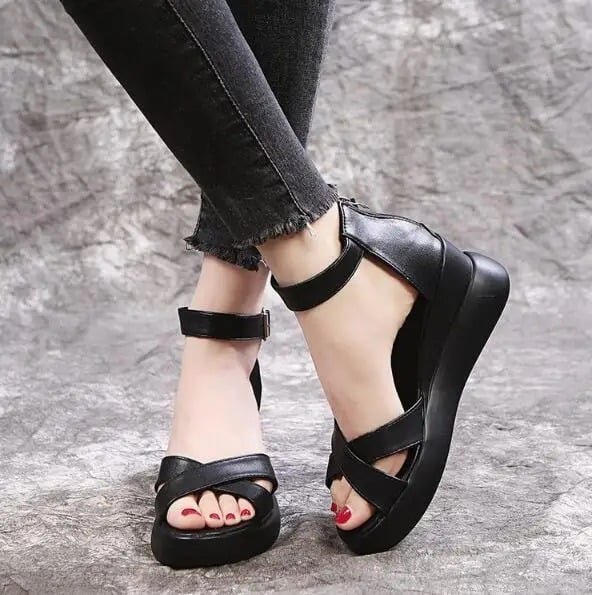 Black wedge sole sandals, with a buckle strap and crossed details on the top.