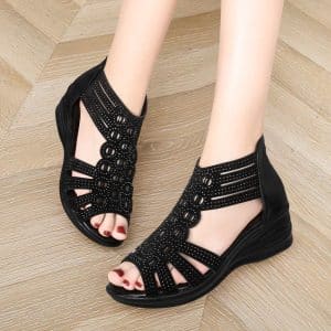 Black wedge sandals with cut-out patterns and rhinestone decorations.