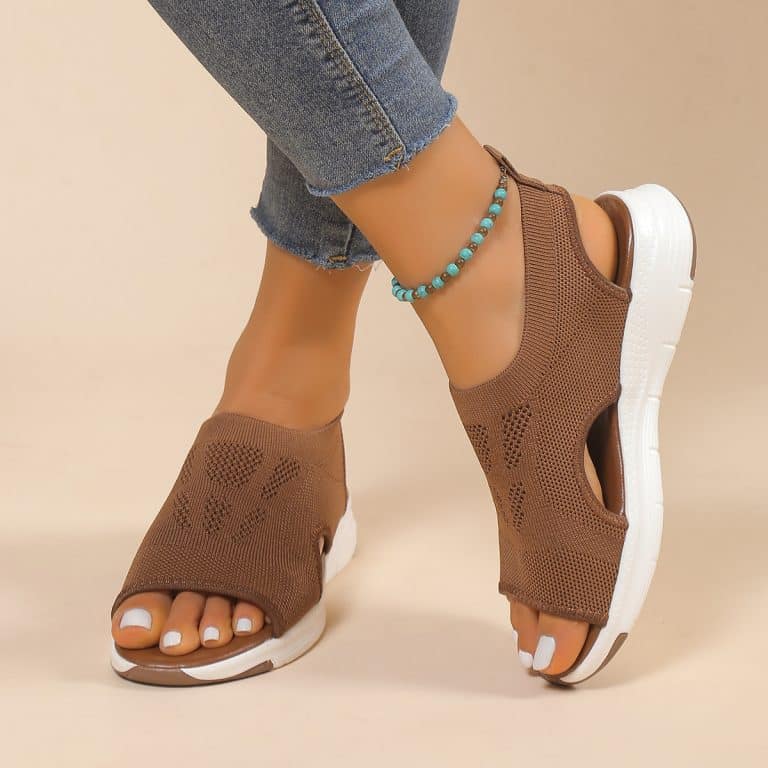 Orthopedic sandals in brown mesh on a beige floor, worn with jeans.