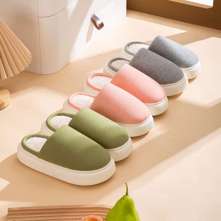 Three pairs of orthopedic cotton slippers in different colors on a light wooden floor.