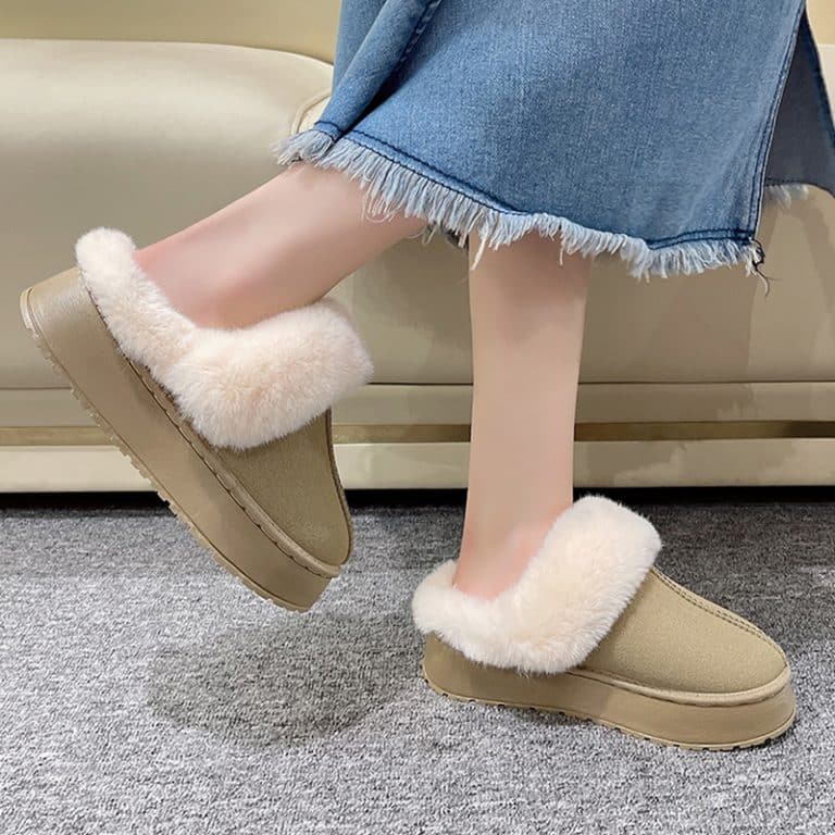 A woman in a blue skirt wearing beige orthopedic slippers with a fluffy interior.