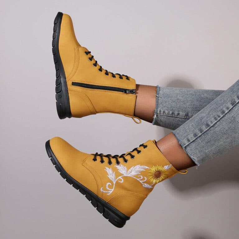Mustard yellow high boots for women with embroidered flowers and zipper closure.