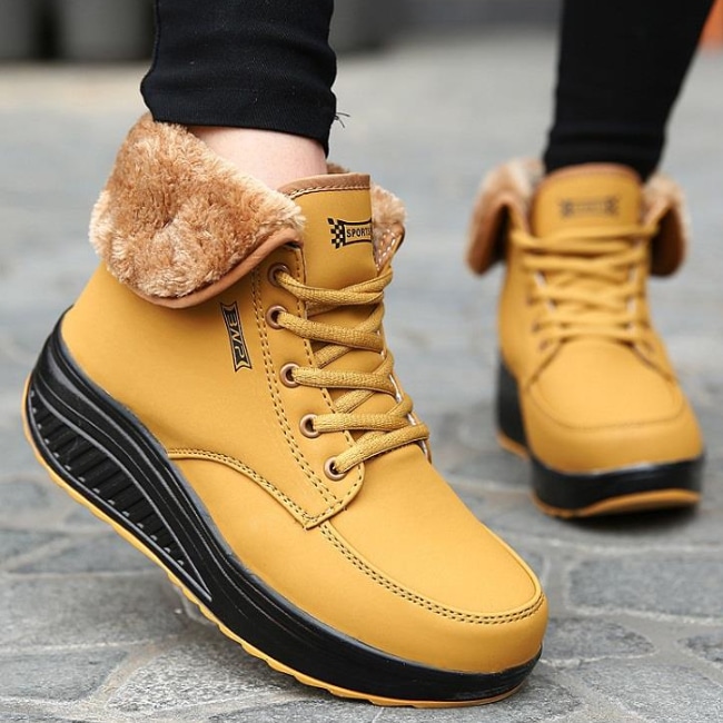 Mustard yellow ankle boots with plush lining and black sole.