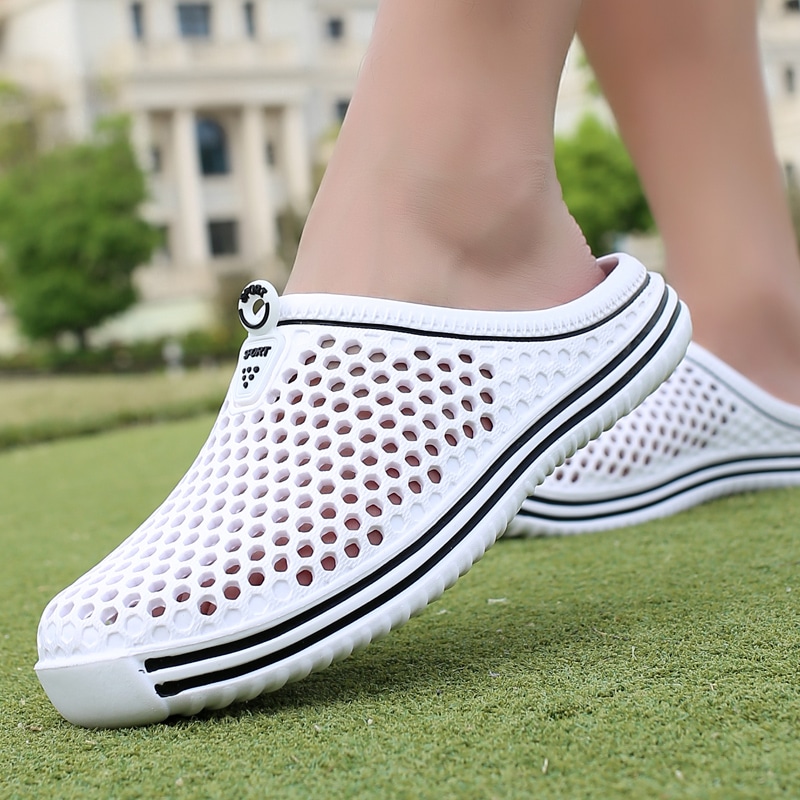Chaussons d'été en maille blanche avec semelle antidérapante et bouton décoratif sur le dessus Summer slippers in white knit with non-slip sole and decorative button on top.