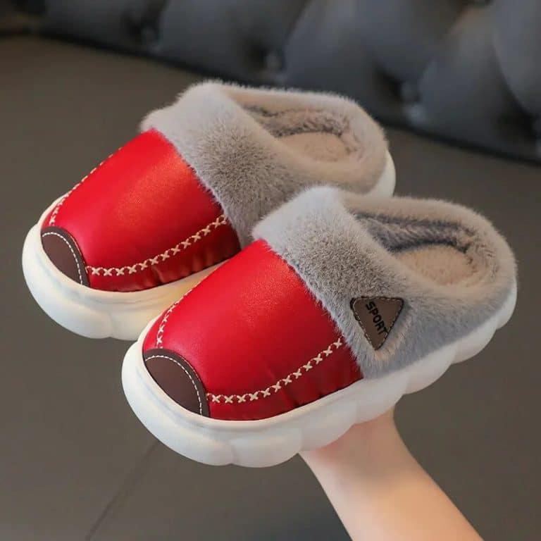 Red slippers held in hand, with gray interior and white sole.