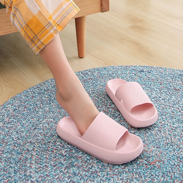 Orthopedic slides for women, soft pink color, worn with a casual outfit on a multicolored rug.