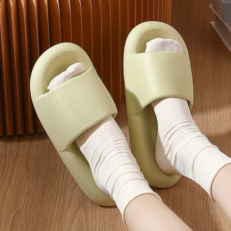 Pale green orthopedic slides worn with white socks, viewed from above.