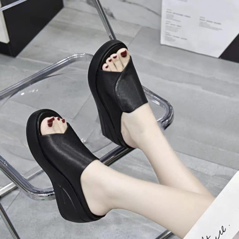 Woman trying on black orthopedic sandals with wedge sole, side view.