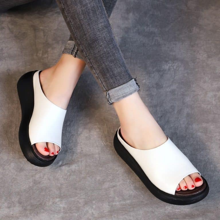 White mules with black soles, featuring a comfortable design and an open-front style.