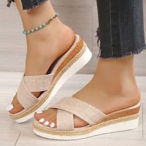 Beige canvas mules with wedge sole, worn with frayed jeans.