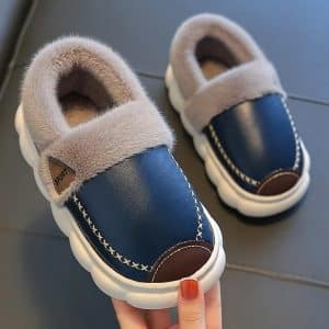 Pair of blue slippers with grey fur lining on grey background