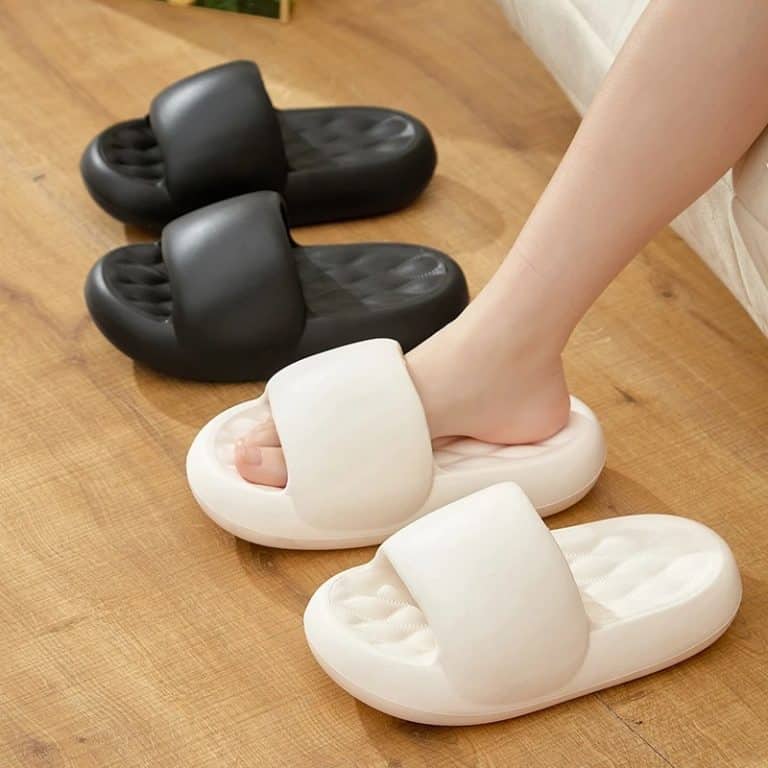Ergonomic slippers for women with a thick black sole and white upper, worn on the foot.