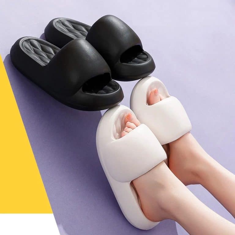 Female feet wearing white orthopedic slides with thick soles, purple and black background.